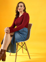 Woman wears 98degreenorth’s maroon ribbed collar neck slim fit sweater paired with a denim skirt, seated on a yellow backdrop.