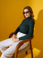 Model wears the 98degreenorth Women’s Military Green Ribbed Turtleneck Sweater, seated against a yellow background.