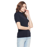 Woman with wavy brown hair wears a 98degreenorth navy blue ribbed half-sleeve turtleneck sweater and light blue jeans.