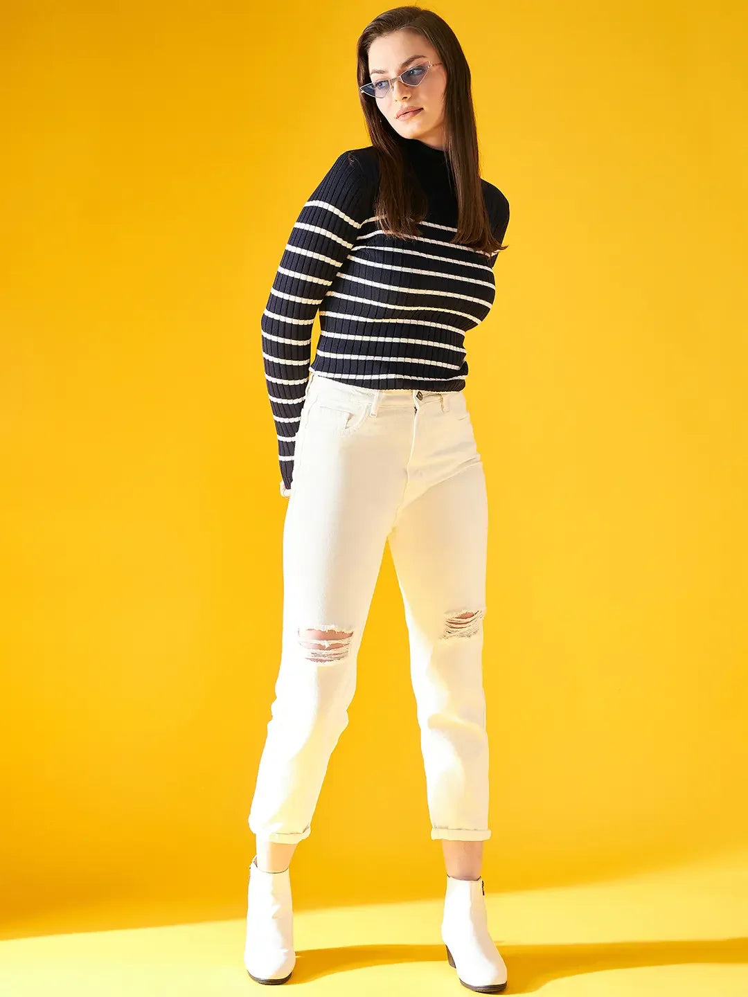 A woman poses in a 98degreenorth Women’s Navy Blue Striped Ribbed Turtleneck Sweater, perfect for winter.