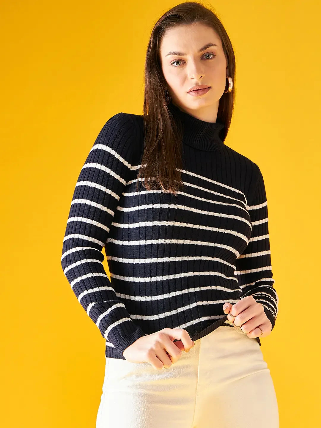 Woman wearing 98degreenorth Women’s Navy Blue Striped Ribbed Turtleneck Sweater poses against a yellow background.