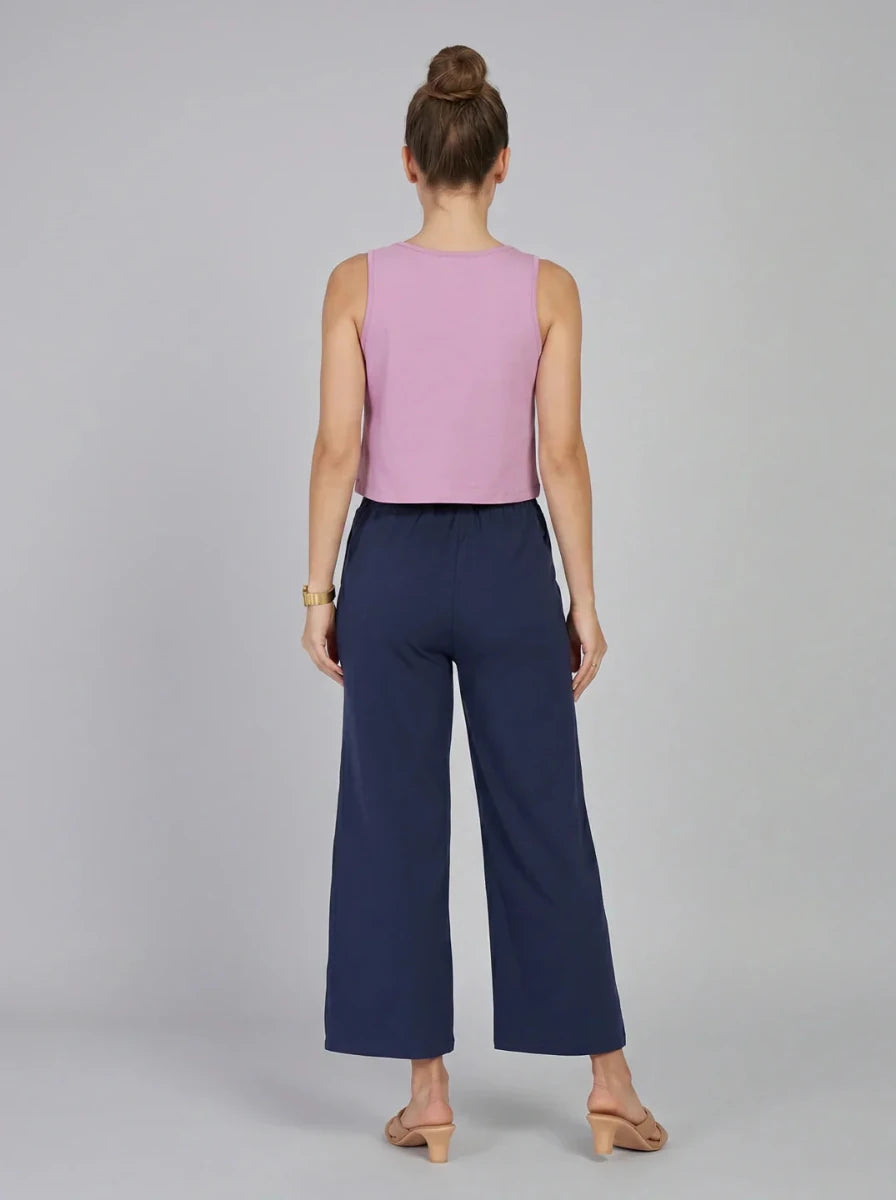 Woman facing away in a pink sleeveless top and 98degreenorth high-rise navy blue wide-leg pants, hair in a bun.