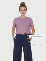 Woman in mauve cropped tee and 98degreenorth navy blue wide-leg, high-rise cotton pants.