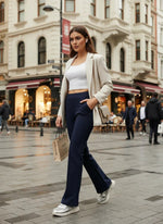 A woman in 98degreenorth Women’s Navy Flared Bootcut Cotton Stretchable Trousers walks on a city street with a shopping bag.