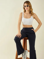 Woman in white crop top and 98degreenorth Navy Flared Bootcut Cotton Stretchable Trousers sits on a stool.