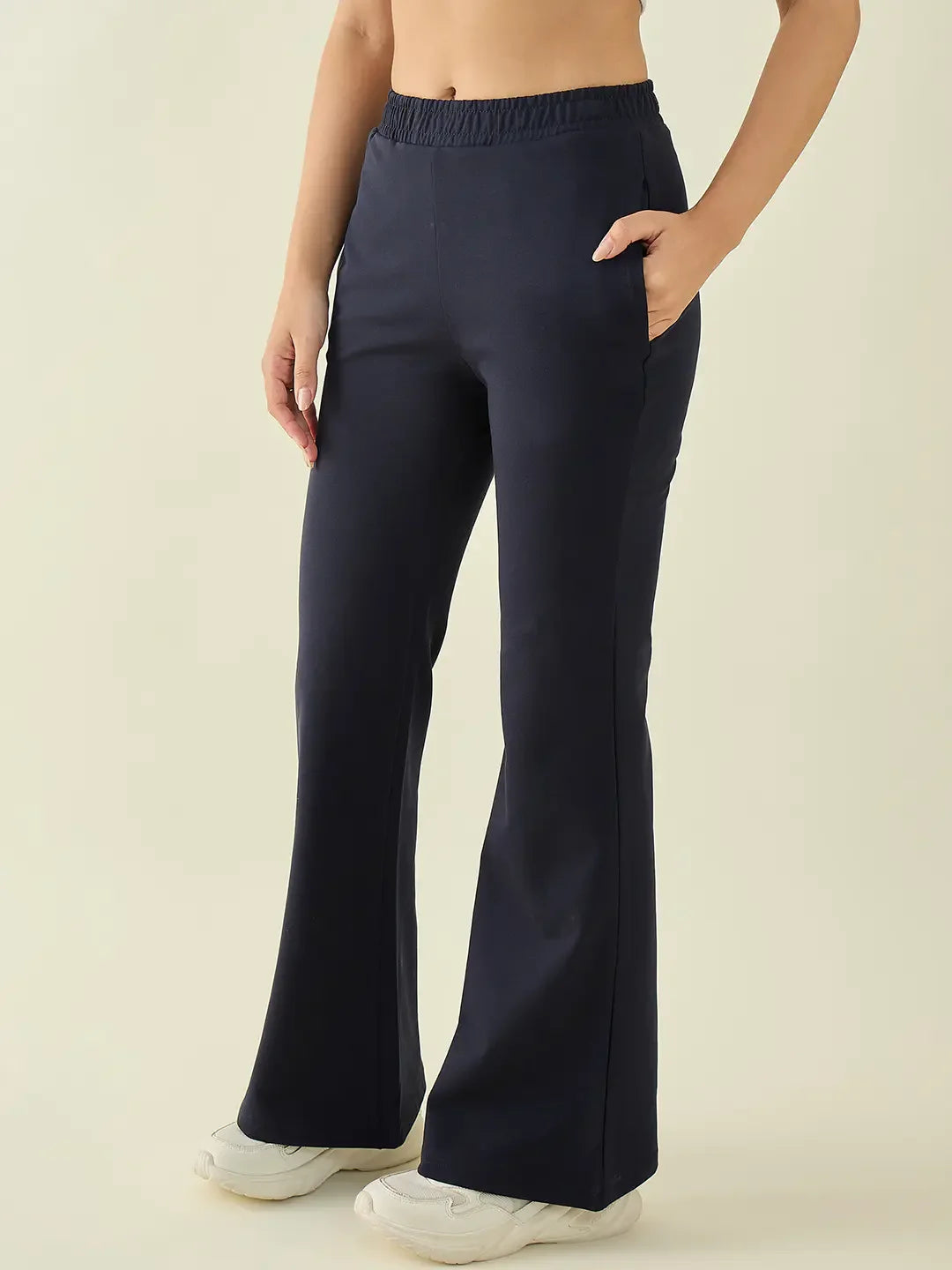 Wearing 98degreenorth Women’s Navy Flared Fit Bootcut Cotton Trousers with pockets and white sneakers, against a plain background.