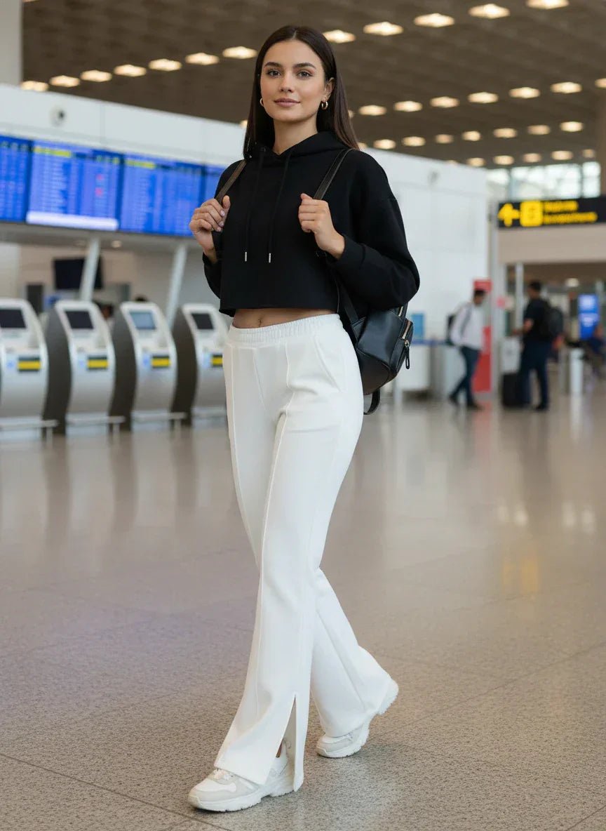 A woman wears 98degreenorth Off-White Bootcut Sweatpants—flared, high-waist with side slit—in an airport terminal.