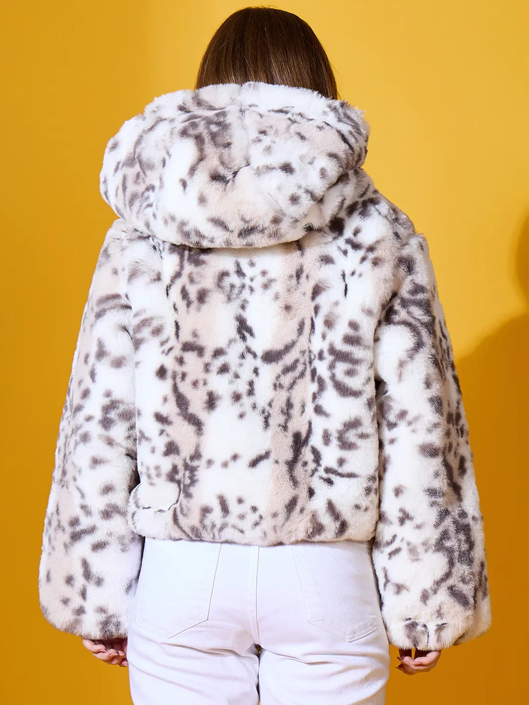 Person wears 98degreenorth Women’s Off-White Faux Fur Jacket, plush winter outerwear, seen from the back on yellow.