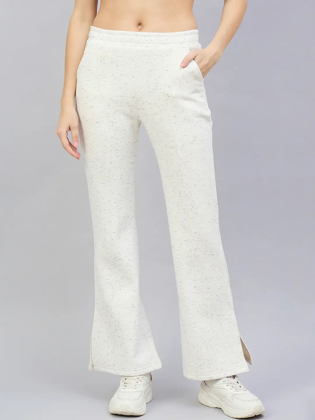 Model in 98degreenorth Women’s Off-White Hairy Texture Bootcut Sweatpants with side slit, white sneakers, gray background.