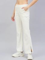 A woman wears 98degreenorth’s off-white hairy texture bootcut sweatpants with side slits, paired with white sneakers.