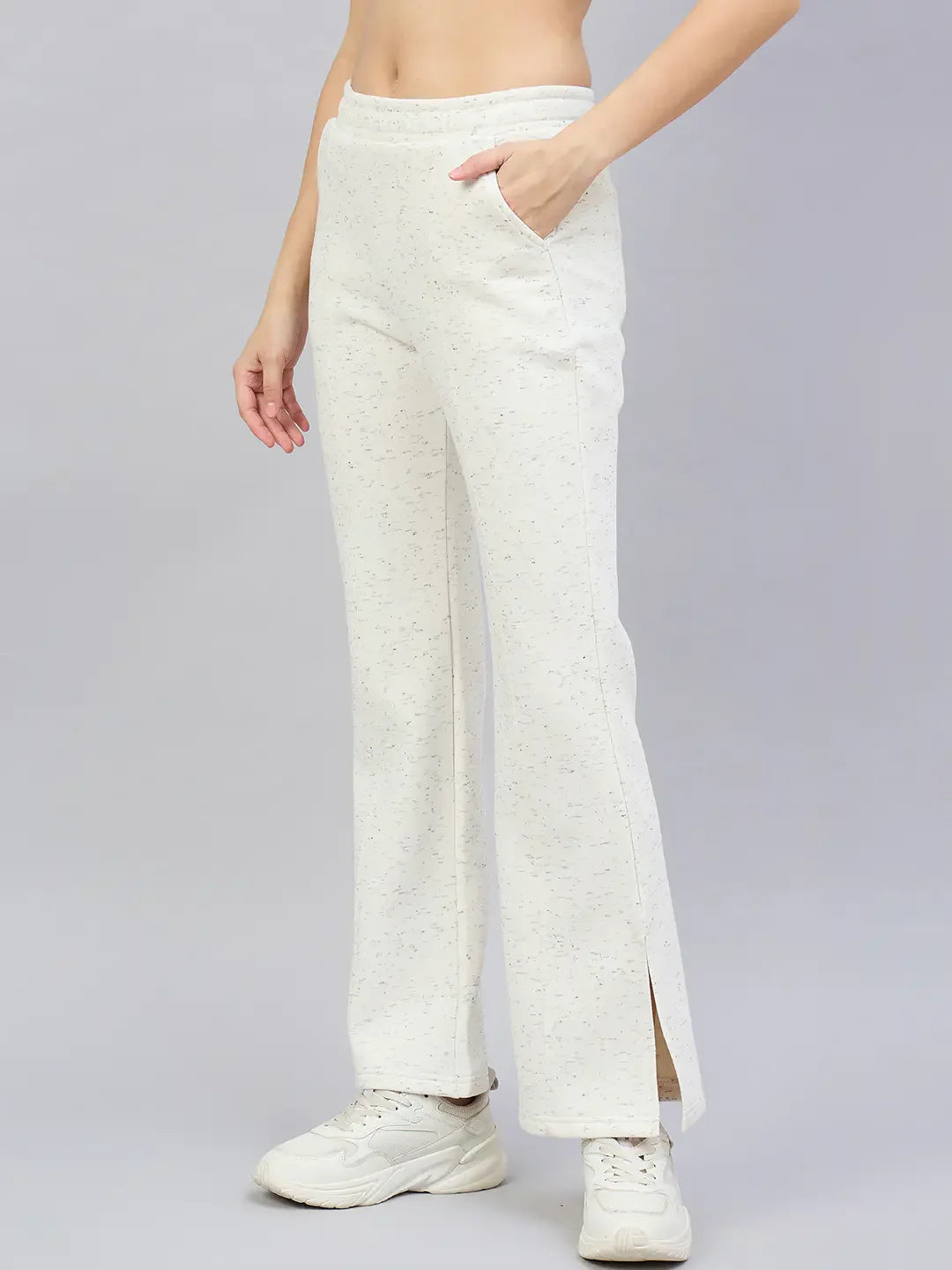 A woman wears 98degreenorth’s off-white hairy texture bootcut sweatpants with side slits, paired with white sneakers.