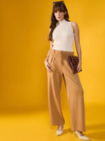 Woman in beige wide-leg pants, 98degreenorth off-white ribbed high neck tank, heels, and brown clutch on yellow backdrop.