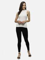 Woman wears 98degreenorth Off-White Ribbed High Neck Sleeveless Knit Top, black leggings, and heels, smiling.