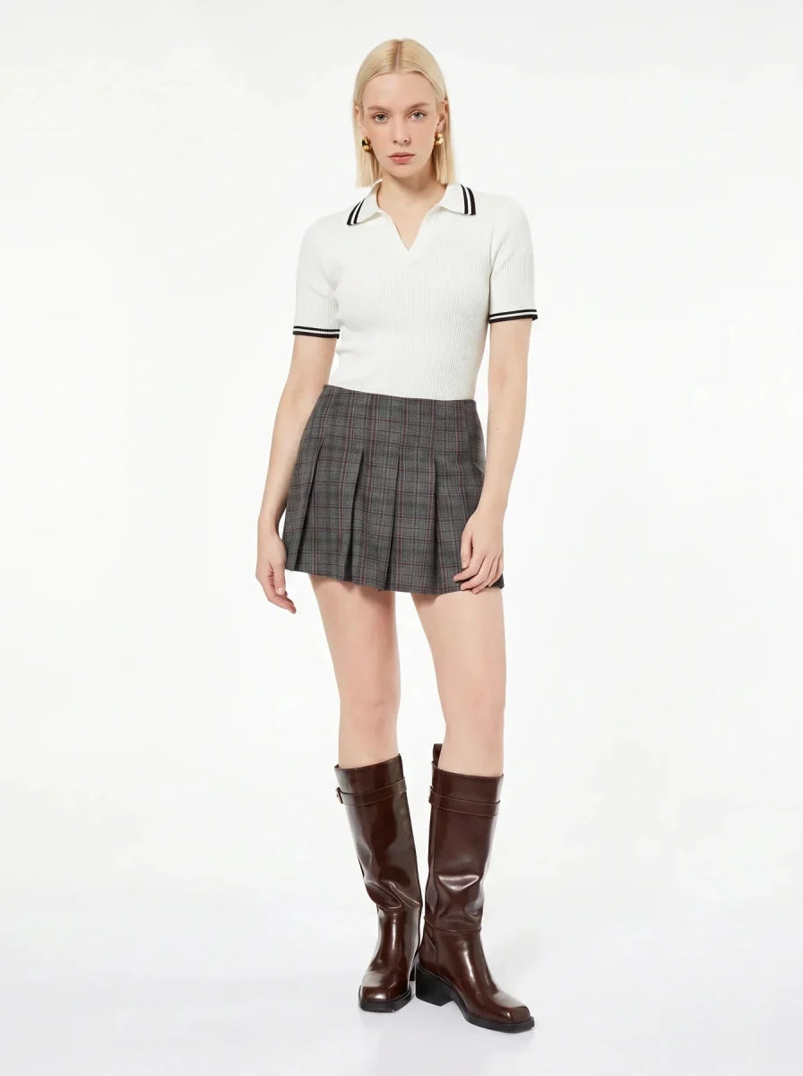 Woman wears 98degreenorth Off-White Ribbed Knit Polo Top with navy tipped collar, plaid skirt, and brown knee-high boots.