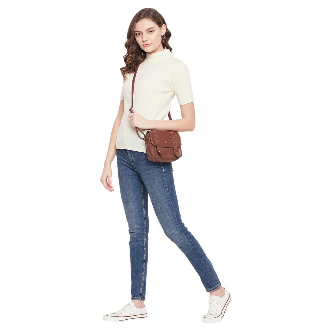 Woman in a 98degreenorth off white ribbed turtle neck sweater, blue jeans & white sneakers with a brown crossbody bag.