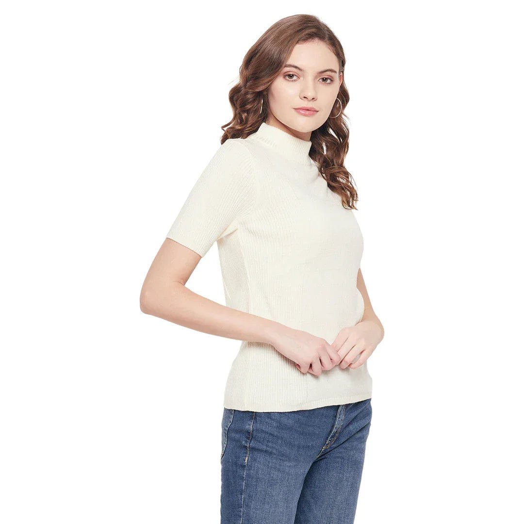 Woman with wavy brown hair in a 98degreenorth off white slim fit ribbed turtle neck sweater and blue jeans, standing sideways.