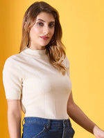 Woman with long brown hair in a 98degreenorth off white ribbed turtleneck slim fit sweater and blue jeans, yellow background.
