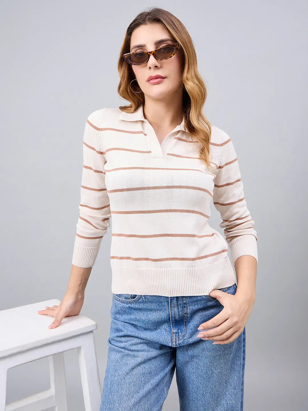 Woman wears 98degreenorth Off-White Striped Collared Sweater, posing with a white stool against a gray background.