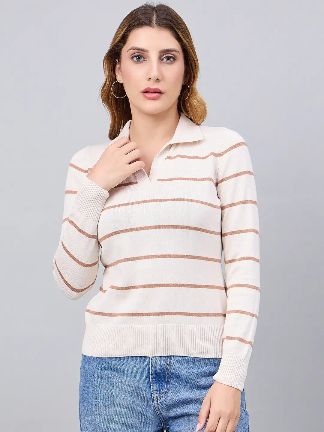 Woman wears 98degreenorth Off-White Striped Collared Sweater with blue jeans, standing against a gray background.
