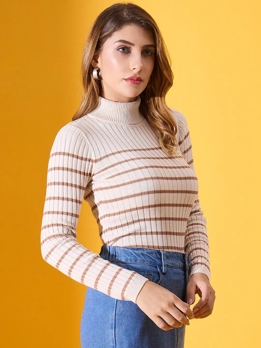 Woman in a 98degreenorth off-white striped ribbed turtleneck sweater and blue jeans against a yellow background.