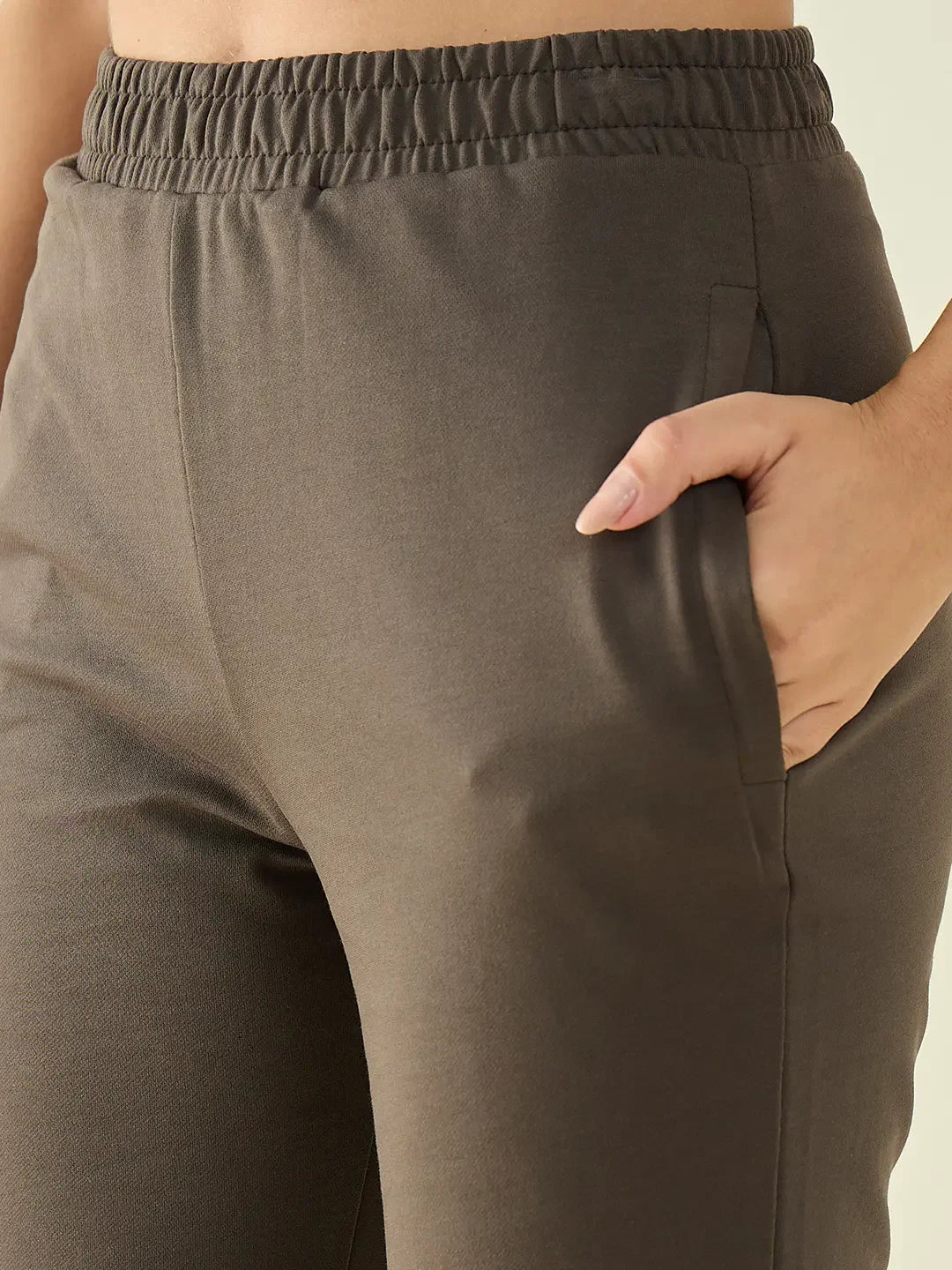 Close-up of a person wearing 98degreenorth Women’s Olive Flared Bootcut Cotton Stretchable Trousers, hand in pocket.