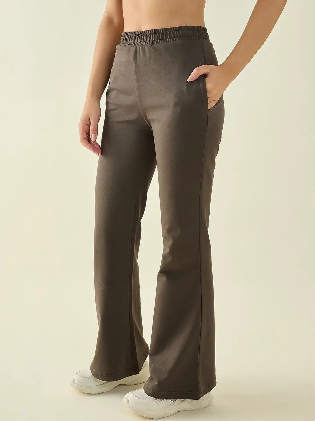 A person wears 98degreenorth Women's Olive Flared Bootcut Cotton Stretchable Trousers with hands in pockets and sneakers.