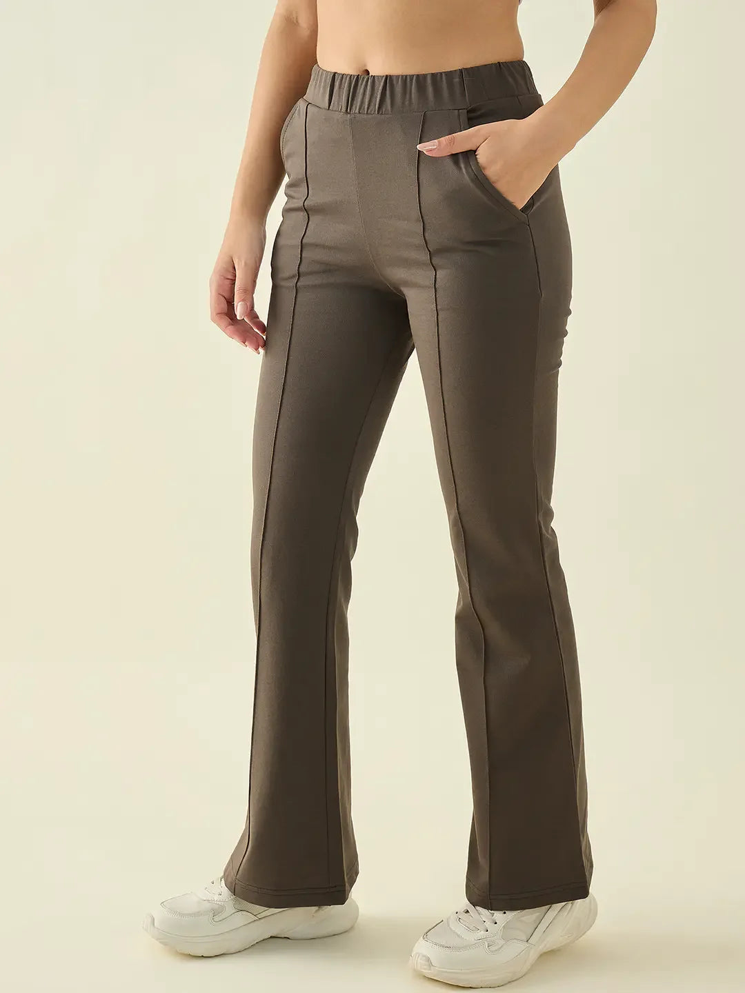Woman wearing 98degreenorth Olive Flared Bootcut Cotton Stretchable Trousers, hand in pocket, white sneakers.