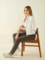 A woman in a white jacket wears 98degreenorth Women's Olive Regular Fit Cotton Stretchable Trousers, seated on a chair.