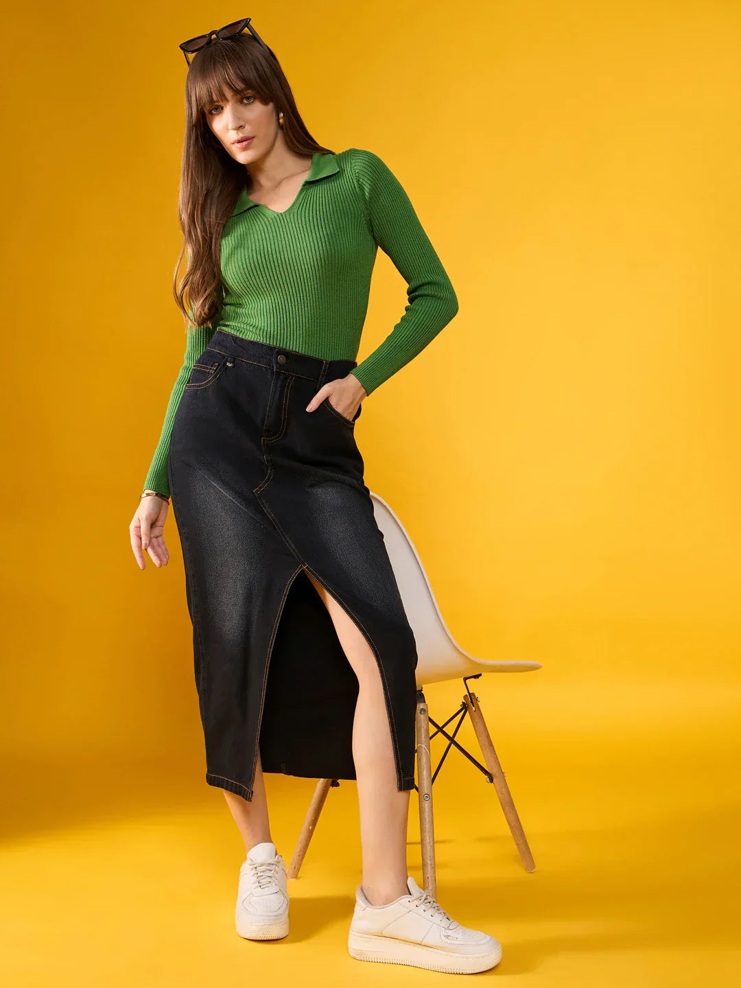 Woman wears 98degreenorth Parrot Green Ribbed Collar Sweater with a dark denim front-slit skirt before a yellow background.