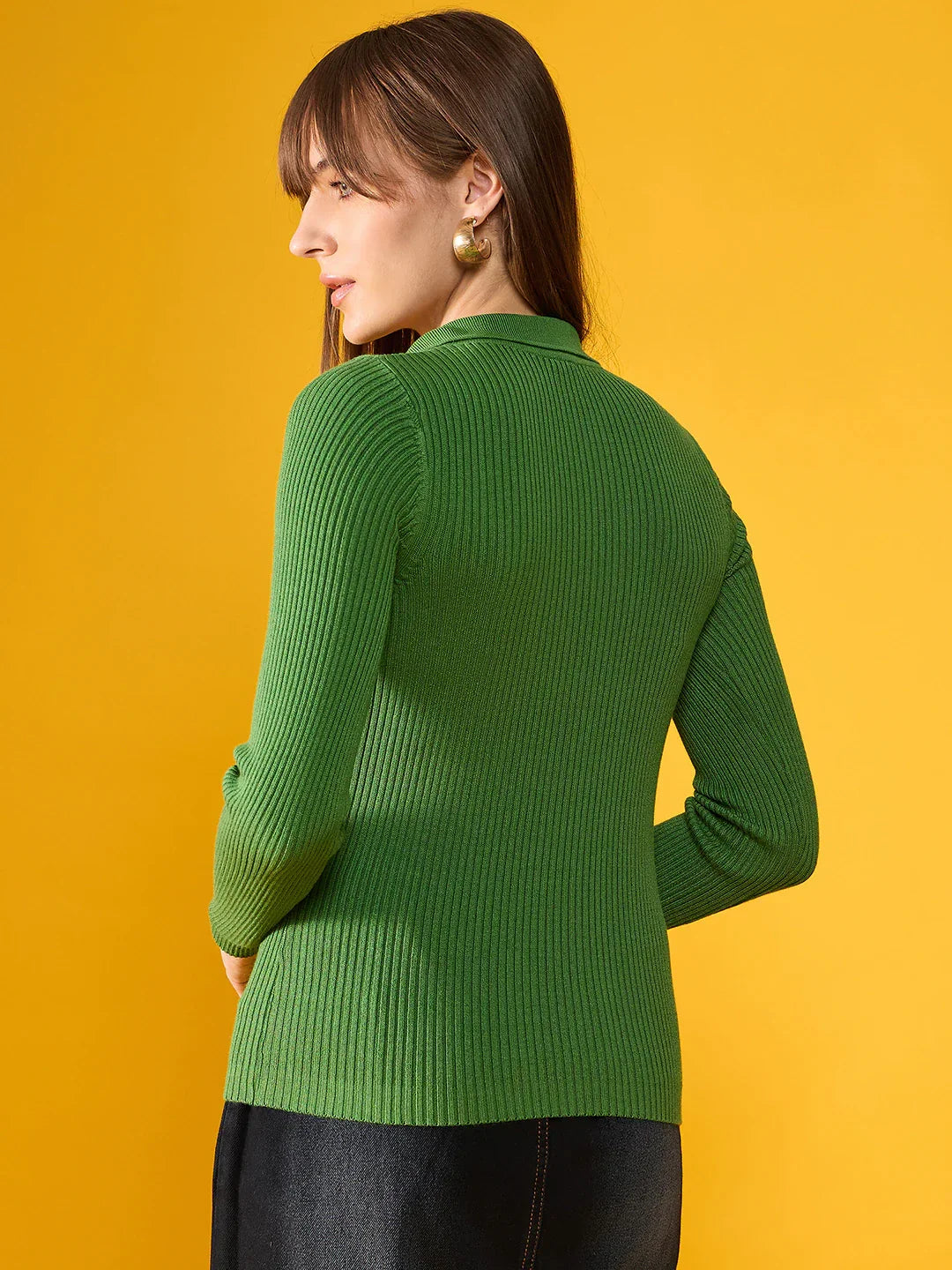 A woman with long brown hair models a 98degreenorth parrot green ribbed sweater, facing away on a yellow background.