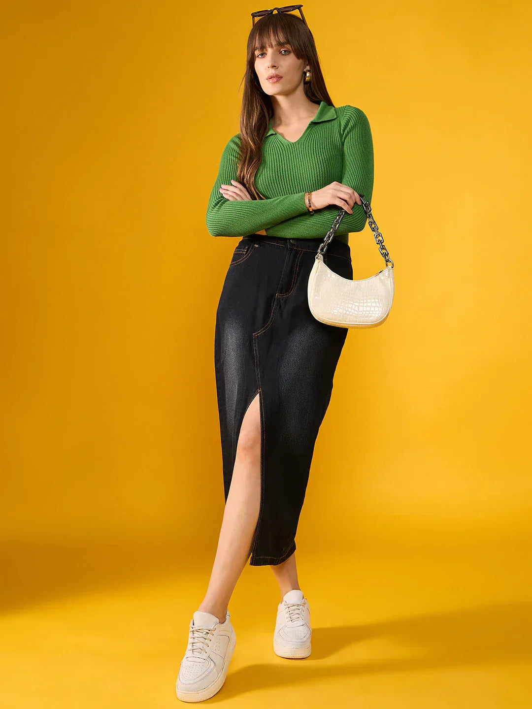 Woman in a 98degreenorth Parrot Green Ribbed Collar Sweater, holding a white handbag against a yellow background.