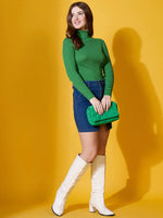 Woman in a 98degreenorth parrot green ribbed turtle-neck pullover styled with a denim skirt, white boots, and green clutch.