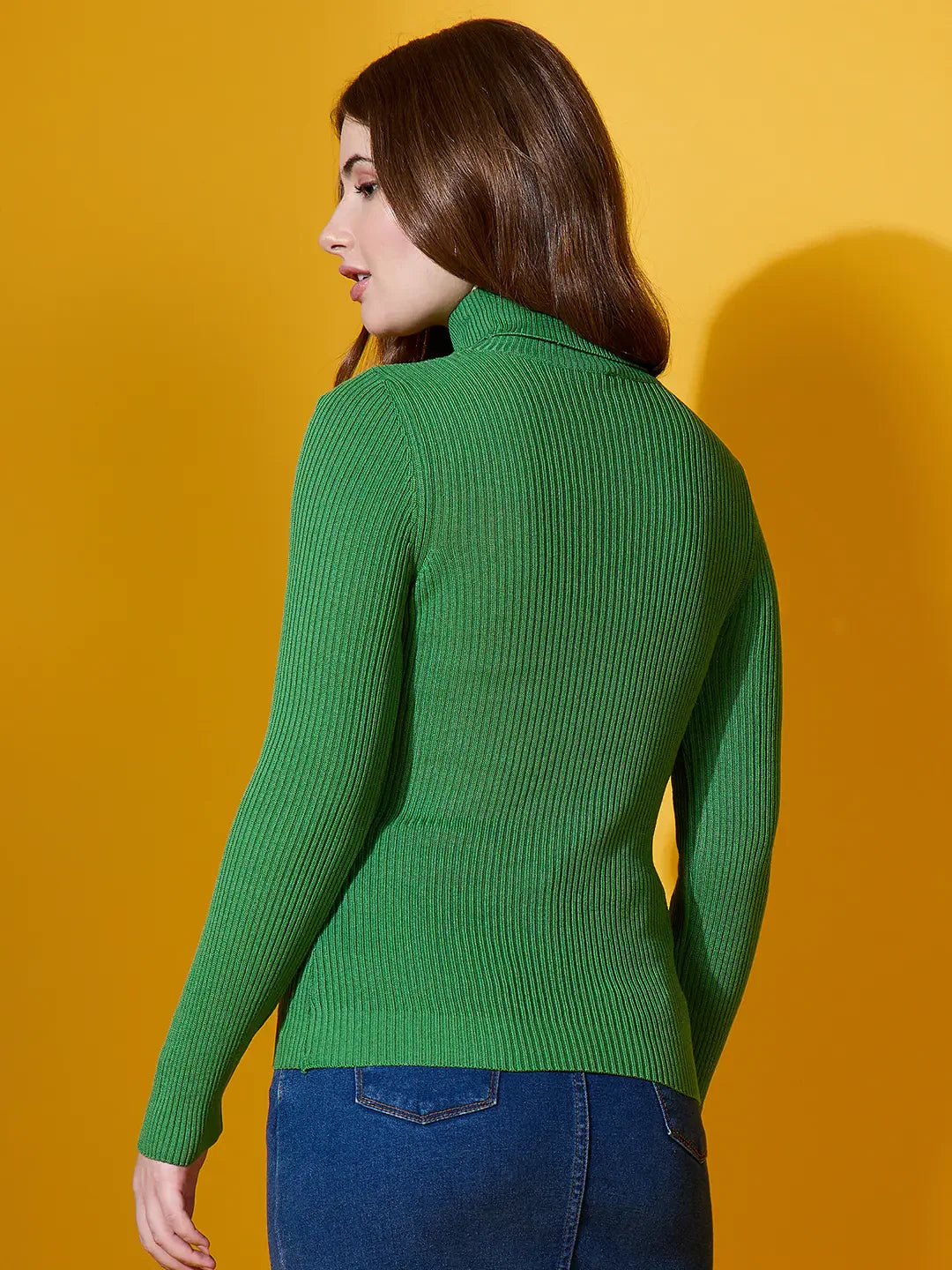 Model wears 98degreenorth Women’s Parrot Green Turtle-Neck Ribbed Pullover, styled with blue jeans on a yellow background.