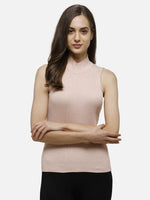 Woman with long brown hair in 98degreenorth's pink ribbed high neck sleeveless knit top and black pants, arms crossed.
