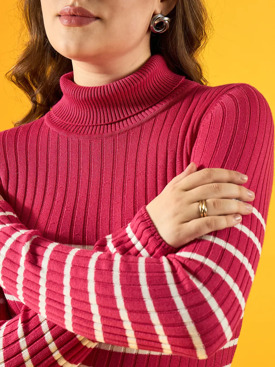 A woman models the 98degreenorth Pink Ribbed Striped Turtleneck Sweater against a vivid yellow backdrop.