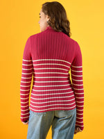 Person facing away in a 98degreenorth Women's Pink Ribbed Striped Turtleneck Sweater, blue jeans, yellow background.