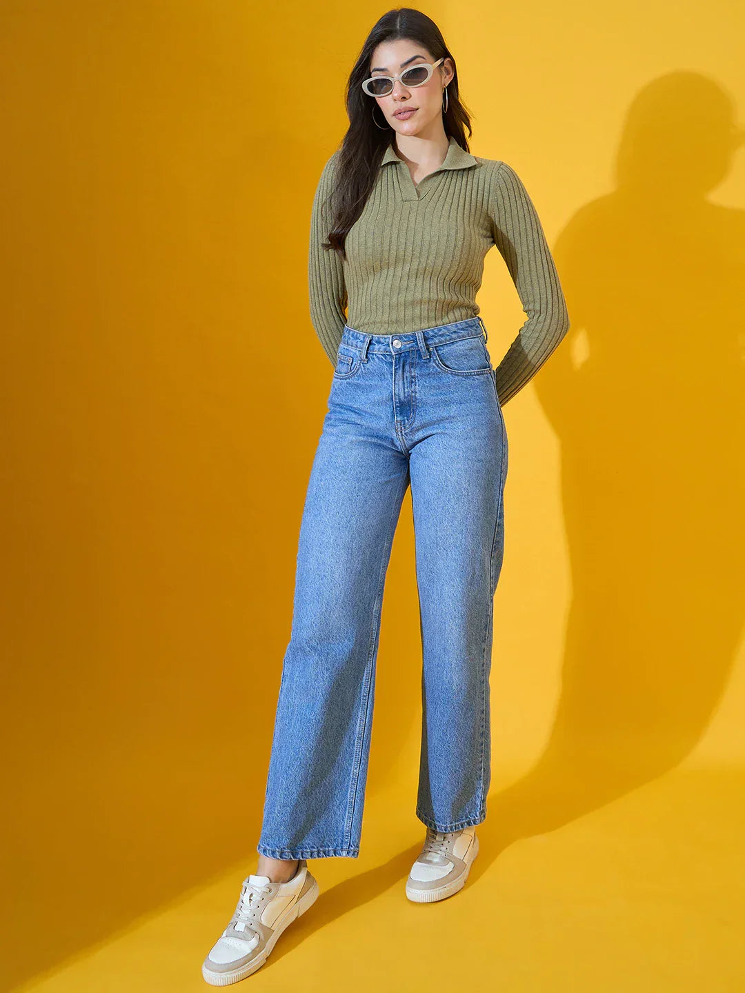 Woman in 98degreenorth’s Pista Melange Ribbed Collar Neck Sweater poses against a yellow background.