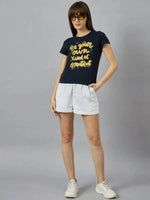 Woman in 98degreenorth’s street-ready pure cotton typography t-shirt with yellow text, white shorts, and sneakers.