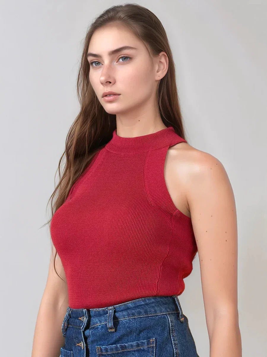 Woman with long brown hair wears a 98degreenorth red ribbed halter neck sleeveless knit top and blue jeans, on gray background.