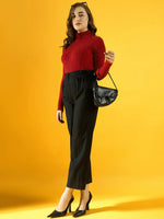 Woman in 98degreenorth’s red ribbed turtleneck sweater poses with a black bag against a yellow background.