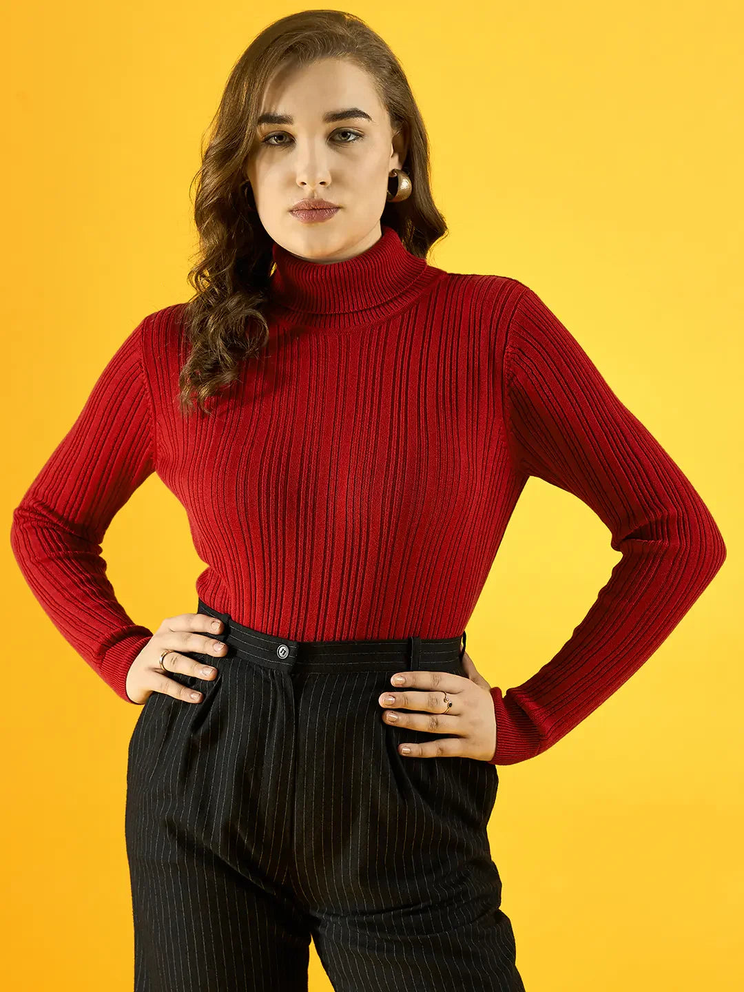 A woman models the 98degreenorth Women’s Red Ribbed Turtleneck Sweater with black pinstripe pants against yellow.