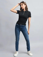 Woman wears 98degreenorth Ribbed Half-Zip Polo Top in black, blue jeans, and white sneakers against a gray background.