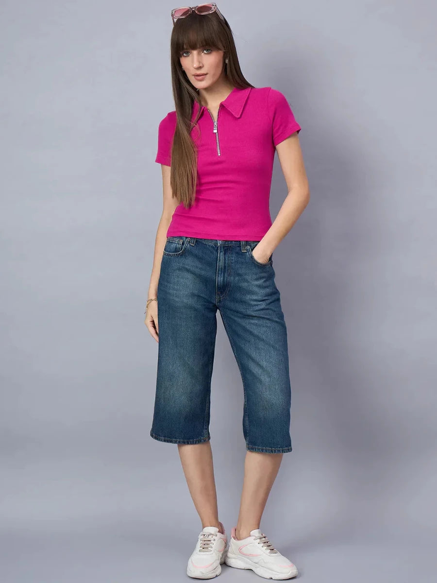 Woman wears 98degreenorth Ribbed Half-Zip Polo Top in fuchsia pink, denim knee-length shorts, and white sneakers.