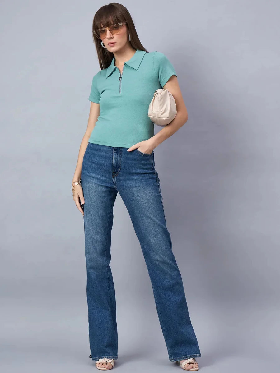 Woman wears 98degreenorth Sea Green Ribbed Half-Zip Polo Top with blue flared jeans, sunglasses, and beige purse.