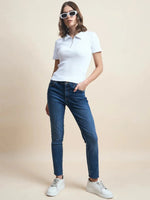 A woman wears 98degreenorth’s Women's Ribbed Half-Zip Polo Top in white, styled with blue jeans and white sunglasses.