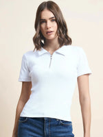 Woman with wavy brown hair in a 98degreenorth white ribbed half-zip polo crop top and blue jeans, plain background.