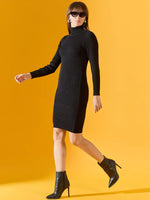 Woman in a 98degreenorth black ribbed turtleneck bodycon sweater dress and black heeled boots against a yellow background.