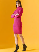Woman in a 98degreenorth Women’s Ribbed Knitted Bodycon Dress – Fuchsia with black ankle boots against a yellow background.