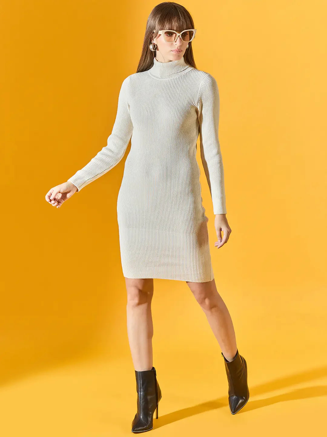 Woman in a 98degreenorth off-white ribbed knitted bodycon turtleneck dress, black ankle boots, and sunglasses.