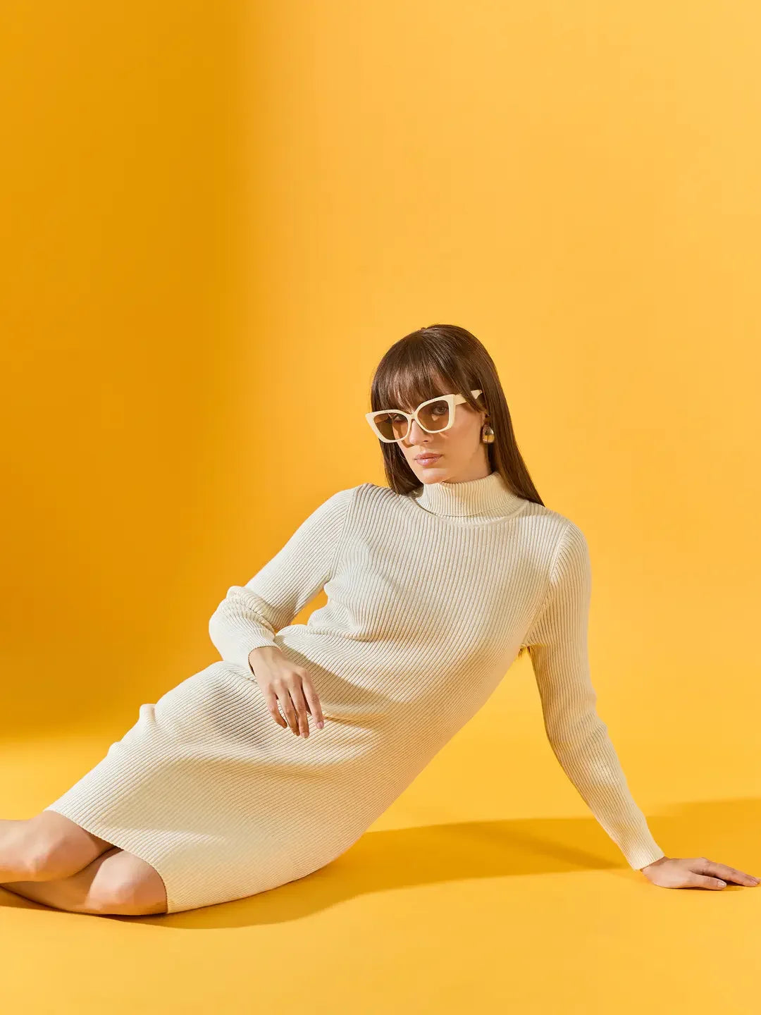 Woman wears 98degreenorth Off-White Ribbed Knitted Bodycon Dress & white sunglasses, seated against a yellow background.